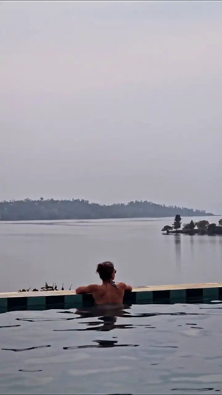 A guest enjoying the swimming pool while watching the views of Lake Kivu